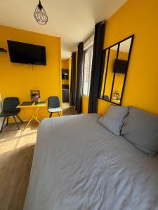 a bedroom with a bed and a yellow wall at La Rose Des Vents in Fécamp
