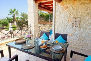 a patio with a table and chairs on a balcony at Villa Petalouda - Traditional Villa with Private Pool in Tragaki