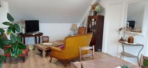 ein Wohnzimmer mit einem gelben Stuhl und einem Tisch in der Unterkunft Appartement privatif étage maison - 2 chambres - 5 couchages - Jardin in Chavagnes-en-Paillers