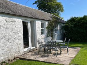 a table and chairs on a patio outside of a building at Barcloy Honey House in Kirkcudbright