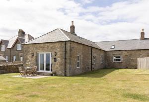 een oud stenen huis met een grote tuin bij The Rushes in Bamburgh