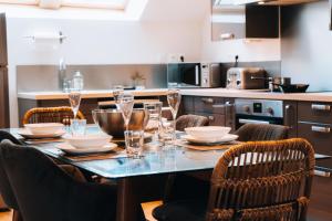 a table with glasses and plates on it in a kitchen at Le Grenier d’Anatole : Parking / Haut Standing in Châteauroux