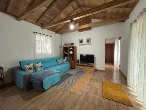 a living room with a blue couch and a television at Casa do Branco in Faja Grande