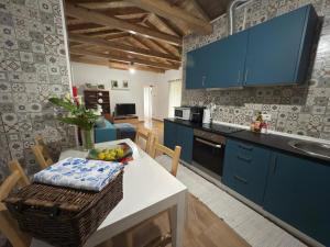 a kitchen with blue cabinets and a table with a bowl of fruit at Casa do Branco in Faja Grande