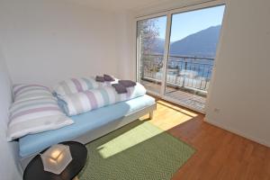 Una sala de estar con un sofá y una ventana grande. en Casa Serena, 3-Zimmerwohnung-Duplex by HolAp SA, en Brione sopra Minusio 4 fotos más
