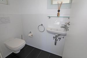 Un baño blanco con inodoro y lavabo. en Casa Serena, 3-Zimmerwohnung-Duplex by HolAp SA, en Brione sopra Minusio