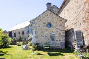 a stone building with a table and chairs in a yard at La Loge de Rose in Peyrelade +15 photos