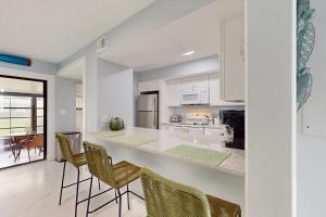 a kitchen with white cabinets and bar stools at Cozy Paradise in Marco Island