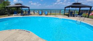 a large blue swimming pool with chairs and a gazebo at The Driftwood Deck 5B in Wasaga Beach