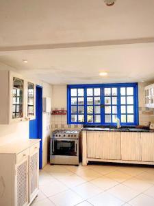 a kitchen with blue windows and a stove top oven at Raizes Chill House in Búzios