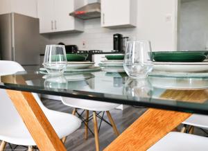 a glass table with chairs and wine glasses on it at 4-Bed Cottage Sleeps 8 Walk to Thames Garden in Hampton