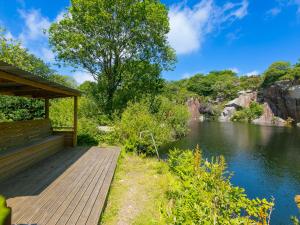 Una pasarela de madera junto a un río con un edificio. en Branock, Tor Down Quarry, en Bodmin