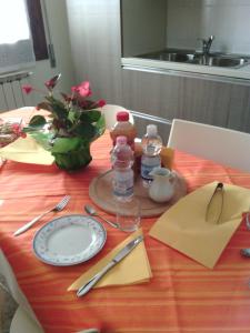 una mesa con un plato y un jarrón de flores en B&B Morosini, en Polesella