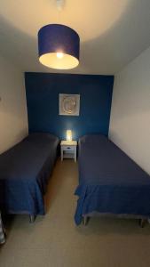 une chambre avec deux lits et un mur bleu dans l'établissement Appartemet en rez de jardin Au Clos du Golfe, à Locmariaquer