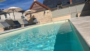 a large swimming pool with chairs and umbrellas at Le Grenier d’Anatole : Parking / Haut Standing in Châteauroux