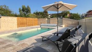 a pool with a table and an umbrella and chairs at Le Grenier d’Anatole : Parking / Haut Standing in Châteauroux
