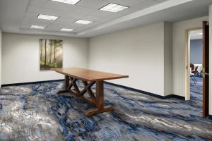 ミッドベールにあるFairfield Inn & Suites by Marriott Salt Lake City Midvaleの敷物の上に木のテーブルが置かれた空の部屋