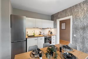 eine Küche mit einem Tisch und einem Kühlschrank aus Edelstahl in der Unterkunft KERA STAY - Apartments Merseburg in Merseburg