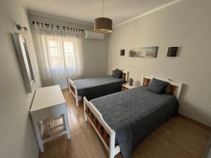 ein Zimmer mit zwei Betten und einem Tisch in der Unterkunft Santa Eulália Terrace in Albufeira
