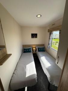 due letti in una piccola stanza con una finestra di Fantasy Island - Eastgate D7 - The Merlin with Hot Tub - Coastal Caravan Breaks a Ingoldmells