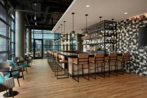雷斯顿AC Hotel by Marriott Reston的餐厅里的酒吧，配有桌椅