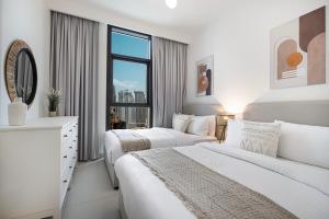 two beds in a white room with a window at Burj Crown Luxury 4 Bedroom, Balcony Views, 5 min to Burj Khalifa in Dubai