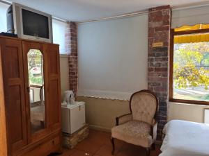 Un dormitorio con una cama y una silla y un televisor. en Lourie Inn, en Rustenburg 9 fotos más