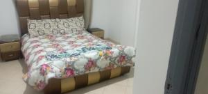1 Schlafzimmer mit einem Bett mit Blumenbettdecke und Kissen in der Unterkunft La perle de l'Atlas in Oulad Akkou