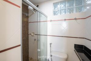 a bathroom with a toilet and a glass shower at Aptos completos na melhor localização e a passos do mar de Guarapari - STP in Guarapari +15 photos
