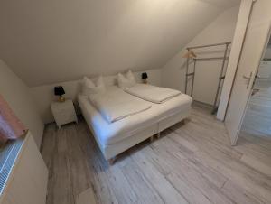 a bedroom with a white bed and a wooden floor at Appartement am Bach in Bad Berneck im Fichtelgebirge