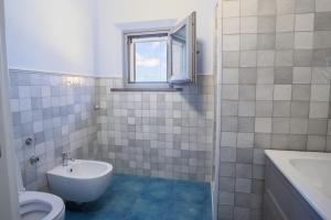 a bathroom with a toilet and a sink and a window at Vento d'Estate B&B in Portoscuso