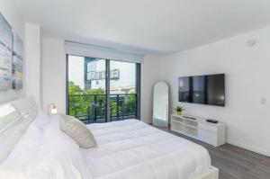 a white bedroom with a large bed and a flat screen tv at Spacious and bright in the heart of Brickell in Miami +41 photos