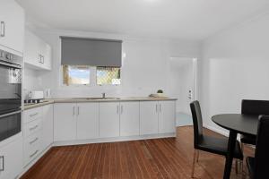 una cucina con mobili bianchi, un tavolo e una finestra di Rangeway Rescue - Older 3BR Home a Geraldton Altre 6 foto