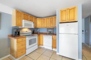 a kitchen with white appliances and wooden cabinets at Stay-Seas Hideaway 214 at Cedar Cove Condos in Cedar Key +11 photos