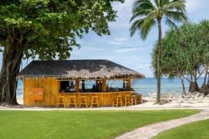 un restaurant sur la plage avec des chaises et des palmiers dans l'établissement Phuket Marriott Resort & Spa, Merlin Beach, à Patong Beach