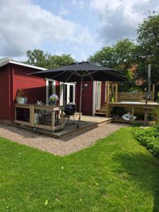 a patio with a table and an umbrella at Tiny house Söderåsen in Ljungbyhed