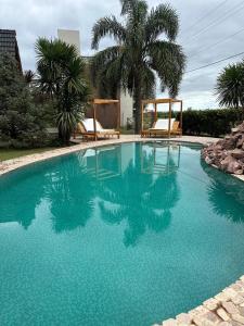 a large blue swimming pool with two chairs and palm trees at DINASTIE COUNTRY APART in Villa Rumipal