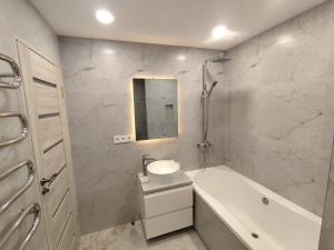 a bathroom with a sink and a tub and a mirror at J&N Hause in Visaginas