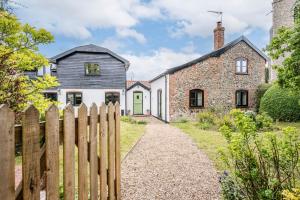 a house with a wooden fence in front of it at The Old Forge, Great Glemham in Great Glemham