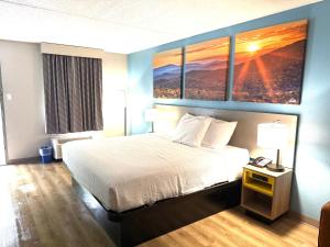 a hotel room with a bed and three paintings on the wall at Days Inn by Wyndham Harriman in Harriman +22 photos