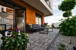 a patio with a couch and a table and flowers at Apartament Indigo 11 by Housine in Zator