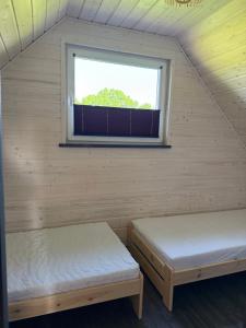 two beds in a room with a window at Łąkowe Wzgórze in Kosewko