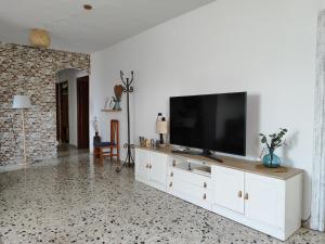 a living room with a television on a white cabinet at La Huerta del Parral in Soportújar