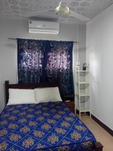 a bedroom with a bed with a blue bedspread at Eliogemi Gardens Guests House in Gbawe