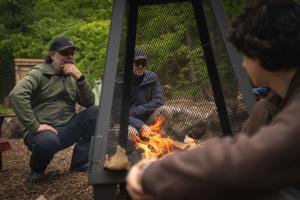 a group of men sitting around a camp fire at Spacious Yurt in the Woods in Sainte-Agathe-des-Monts