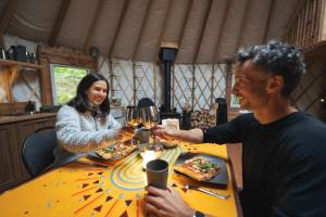 a man and woman sitting at a table with wine glasses at Spacious Yurt in the Woods in Sainte-Agathe-des-Monts