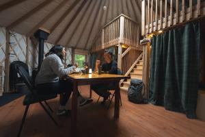 two women sitting at a table in a cabin at Spacious Yurt in the Woods in Sainte-Agathe-des-Monts