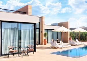 a villa with a swimming pool with chairs and a table at Med IL Caesar ADULT ONLY in Zāwiyat al ‘Awwāmah