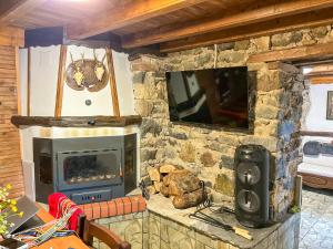 a living room with a stone fireplace with a tv at Каменната къща in Borowo
