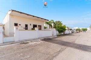 ein Haus in einer Straße mit einem weißen Zaun in der Unterkunft Dimora Lucy by Vivimy in Taviano